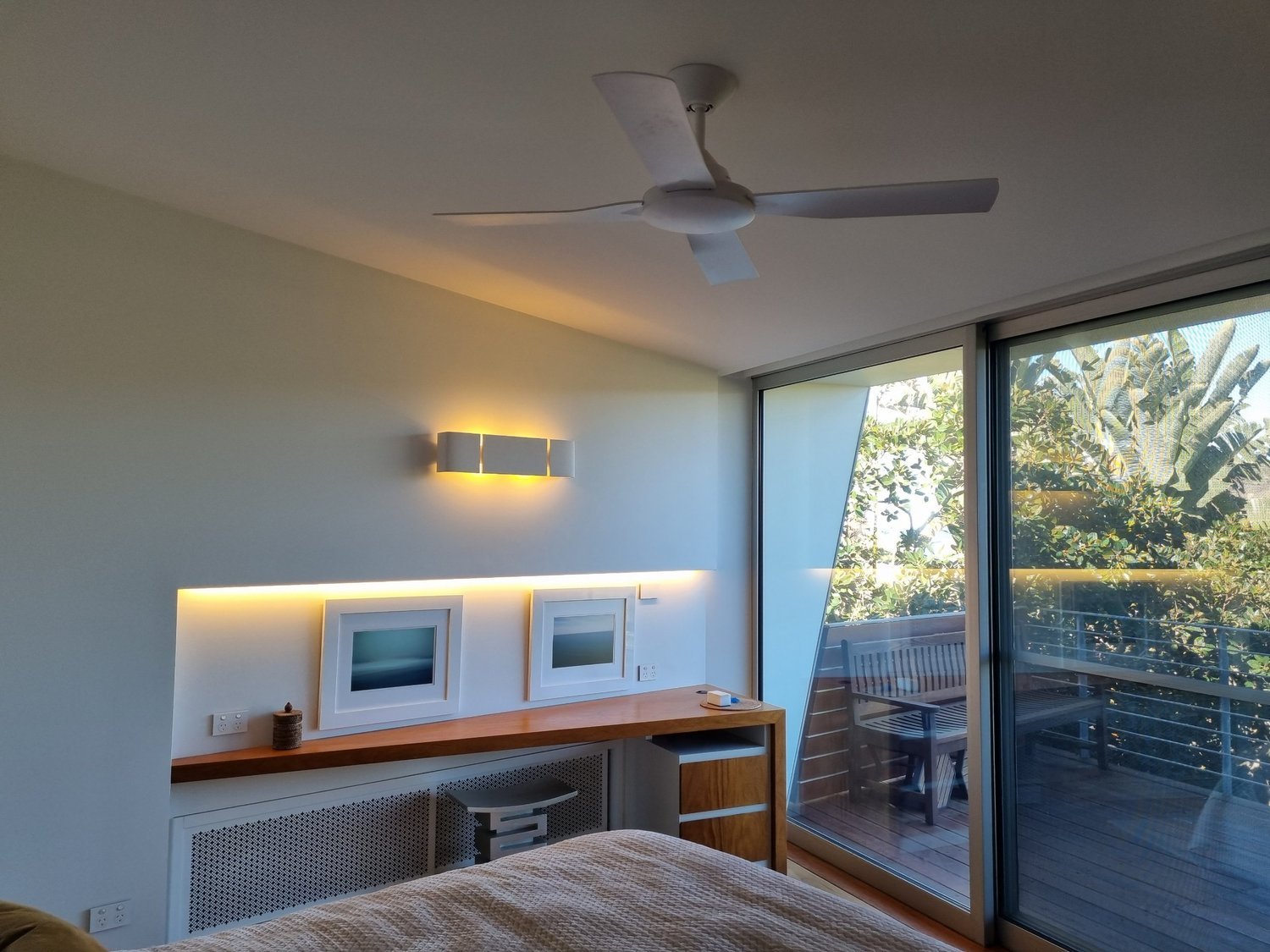 Bedroom with a ceiling fan and layered warm lighting