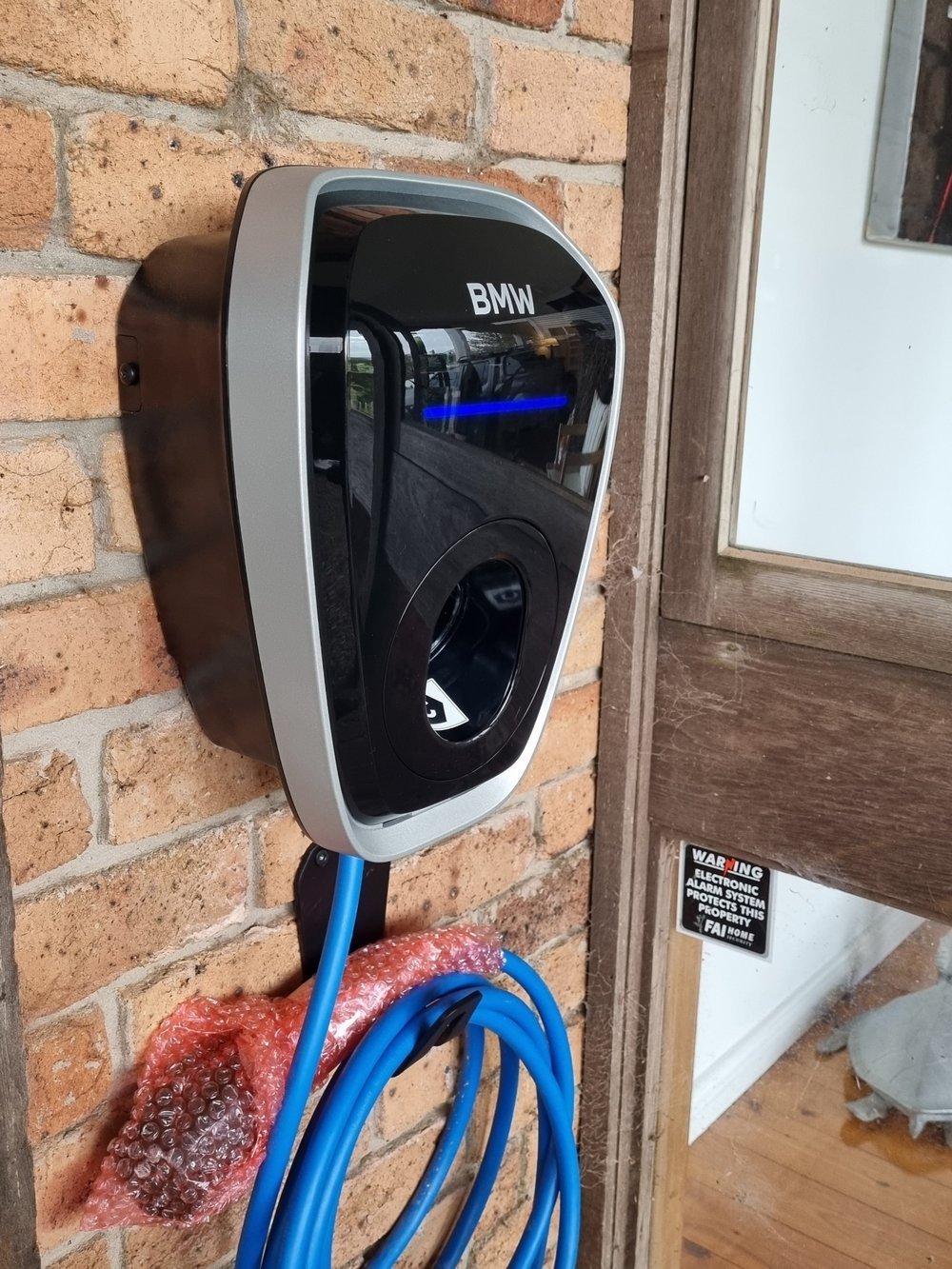 Wall-mounted EV charger with a blue charging cable